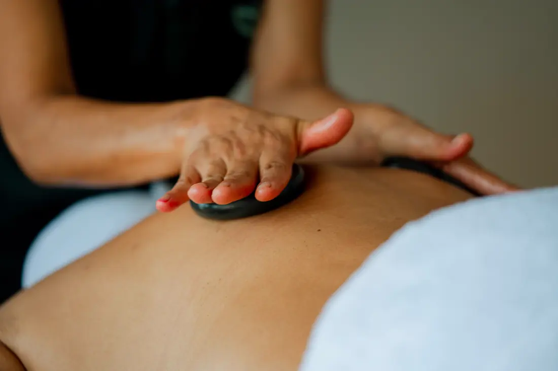 A therapist working warm stones along a guest’s back