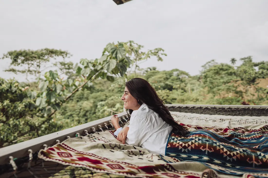 A guest resting on woven blankets on the terrace, looking out over the forest