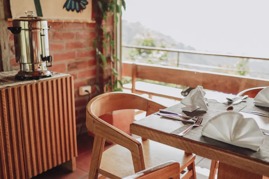 The lodge dining room, tables set beside open windows onto the valley