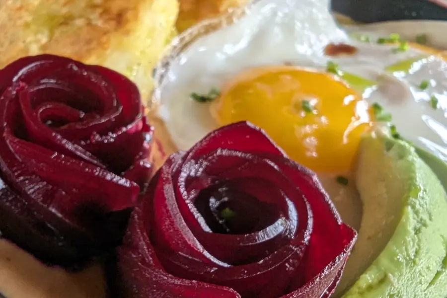 Breakfast of beetroot roses, egg and avocado on toasted bread