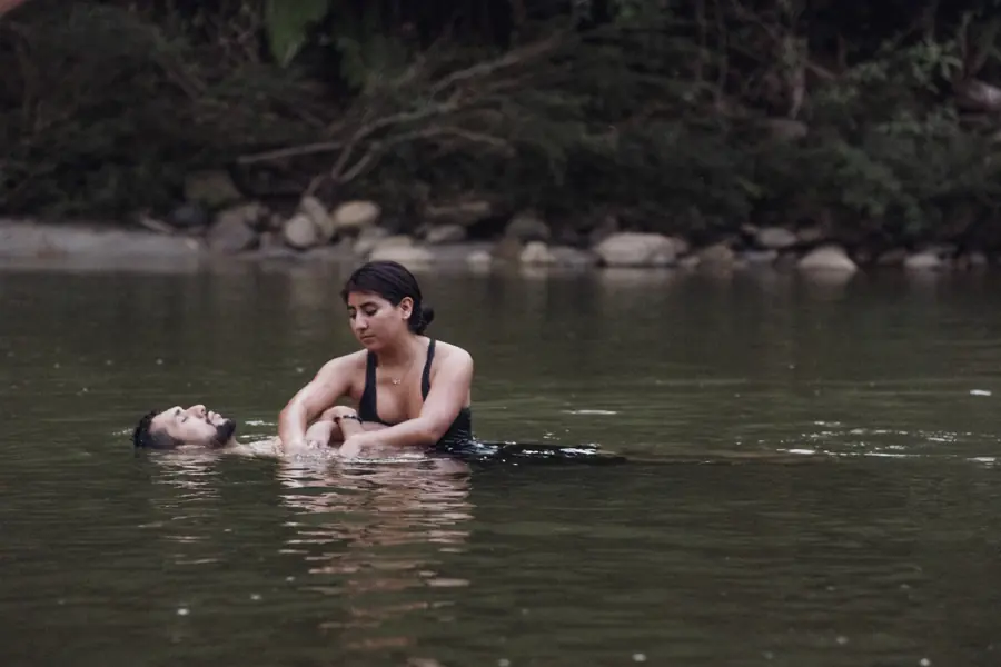 A therapist floating a guest on their back in the river below the lodge